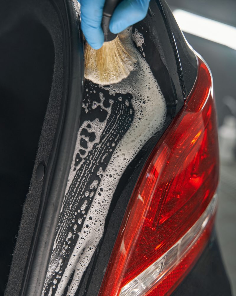 Car detailing studio worker cleaning car with brush